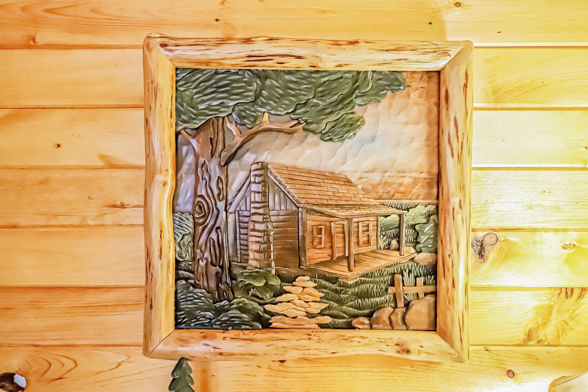 Une cabane en bois avec un arbre, une petite véranda et un mur en pierre.