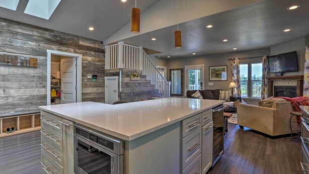 A modern kitchen with a central island, a dining area with a sofa, and a staircase leading to an upper level. - Sierra Sunset Inn - 3 Miles to Placerville! (Diamond Springs)