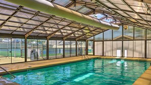 An indoor swimming pool with a covered roof, clear water, and a wooden deck area. - Pet-friendly Branson Retreat w/ Pool & Golf Access (Branson)