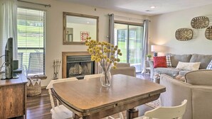 A dining area with a wooden table, chairs, and a vase with yellow flowers. - Pet-friendly Branson Retreat w/ Pool & Golf Access (Branson)