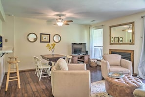 A living room with a ceiling fan, a television, a fireplace, and a dining area with a table and chairs. - Pet-friendly Branson Retreat w/ Pool & Golf Access (Branson)