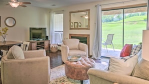 A living room with a television, fireplace, and large sliding glass door to a lawn. - Pet-friendly Branson Retreat w/ Pool & Golf Access (Branson)