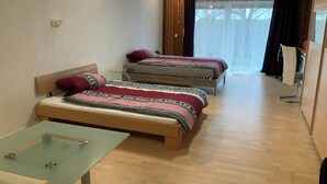 A room with two beds, a glass-top table, and a wooden floor. - Brenda Ferienwohnung (Schillingsfürst)