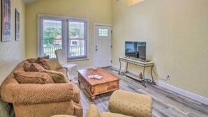 A living room with a sofa, coffee table, TV, and a small table with a lamp. - Family Home: Walk to Downtown & Stetson Univ! (DeLand)