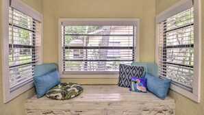 A cozy reading nook with a bench, pillows, and a view through a window with blinds. - Family Home: Walk to Downtown & Stetson Univ! (DeLand)