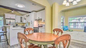 A kitchen with white cabinets, a wooden dining table, and a blue chair. - Family Home: Walk to Downtown & Stetson Univ! (DeLand)