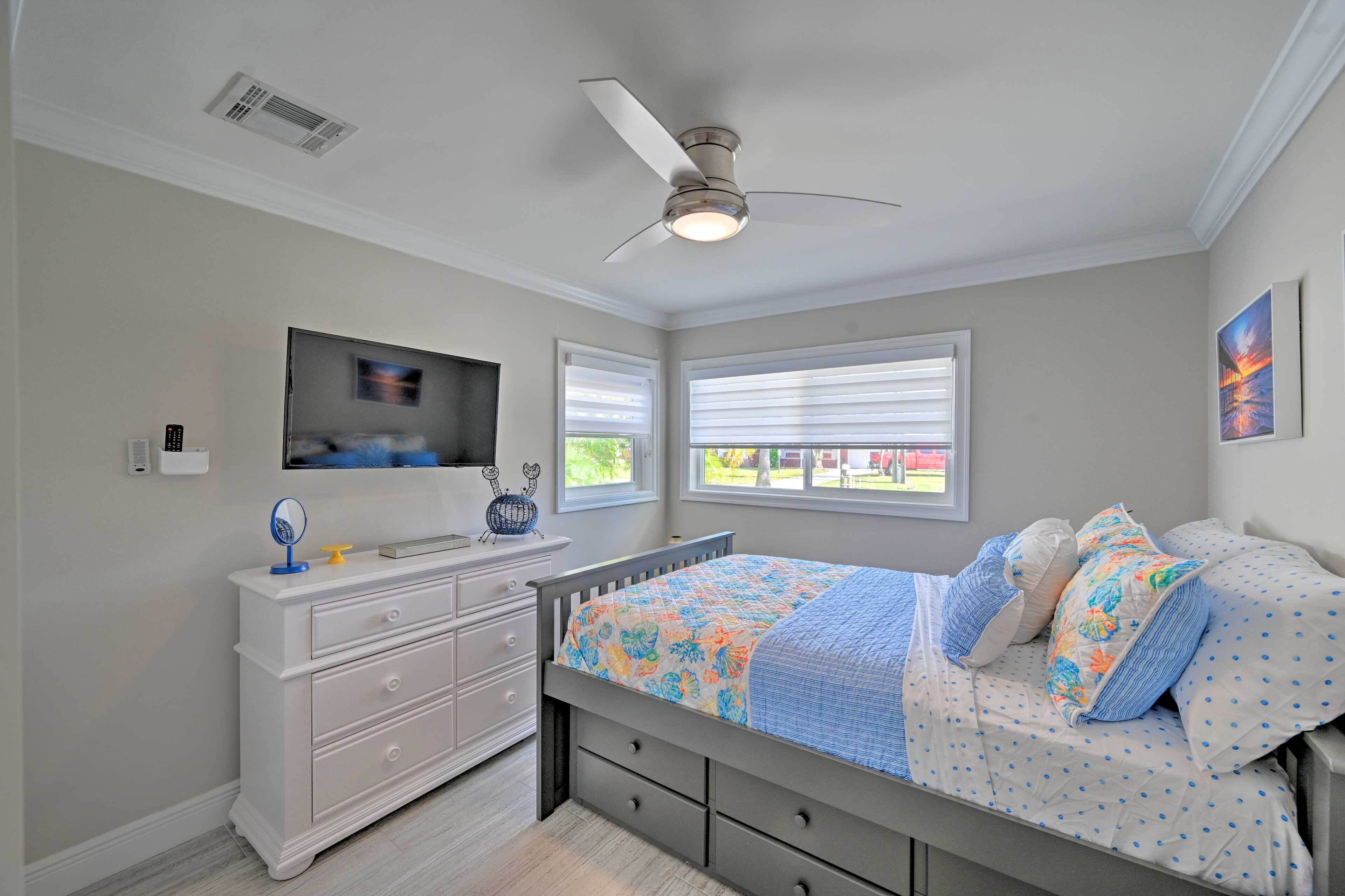 Une chambre à coucher avec un lit, une commode, un ventilateur de plafond et des fenêtres.