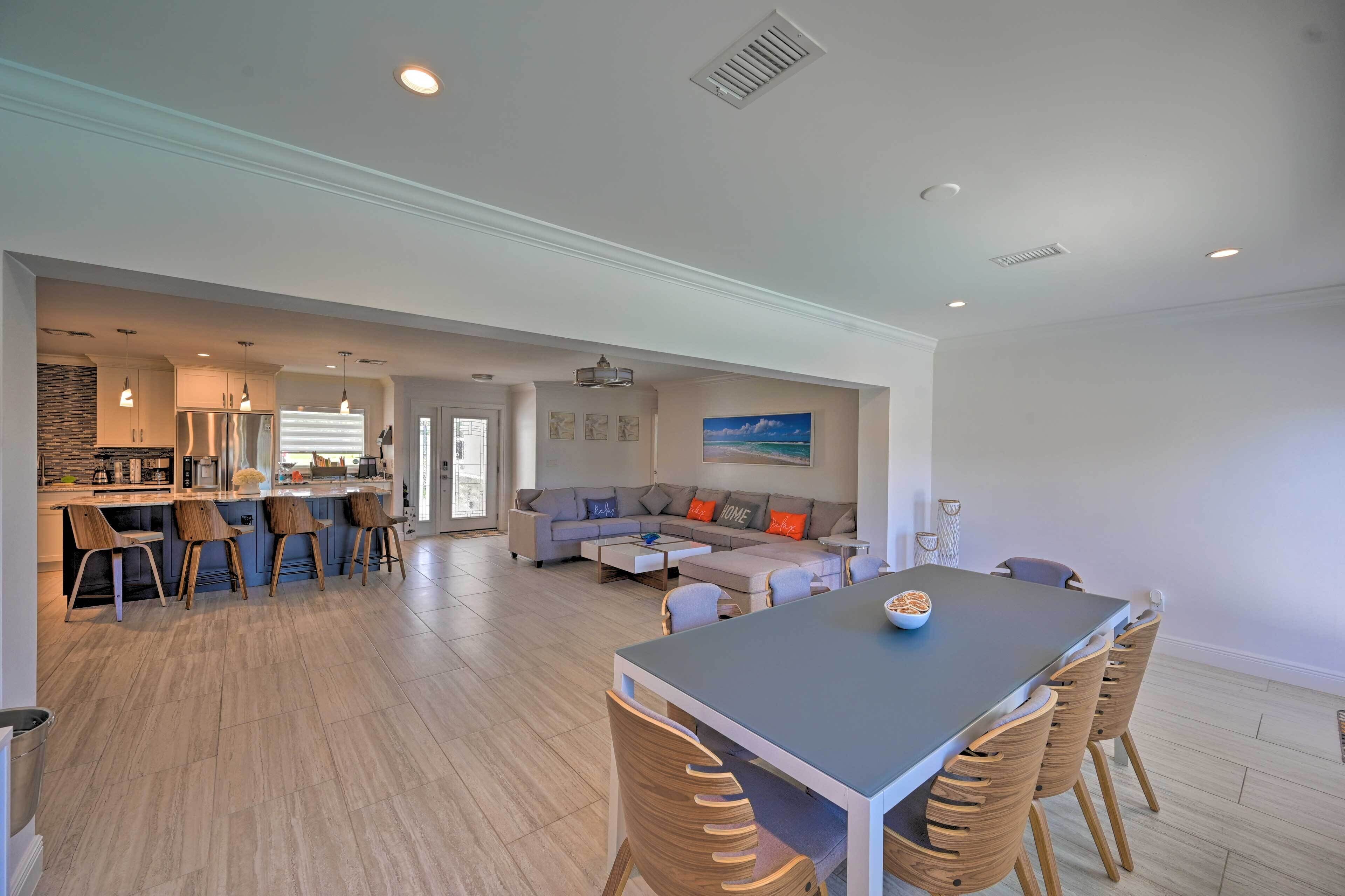 A spacious living area with a dining table, sofas, and a kitchen in the background.