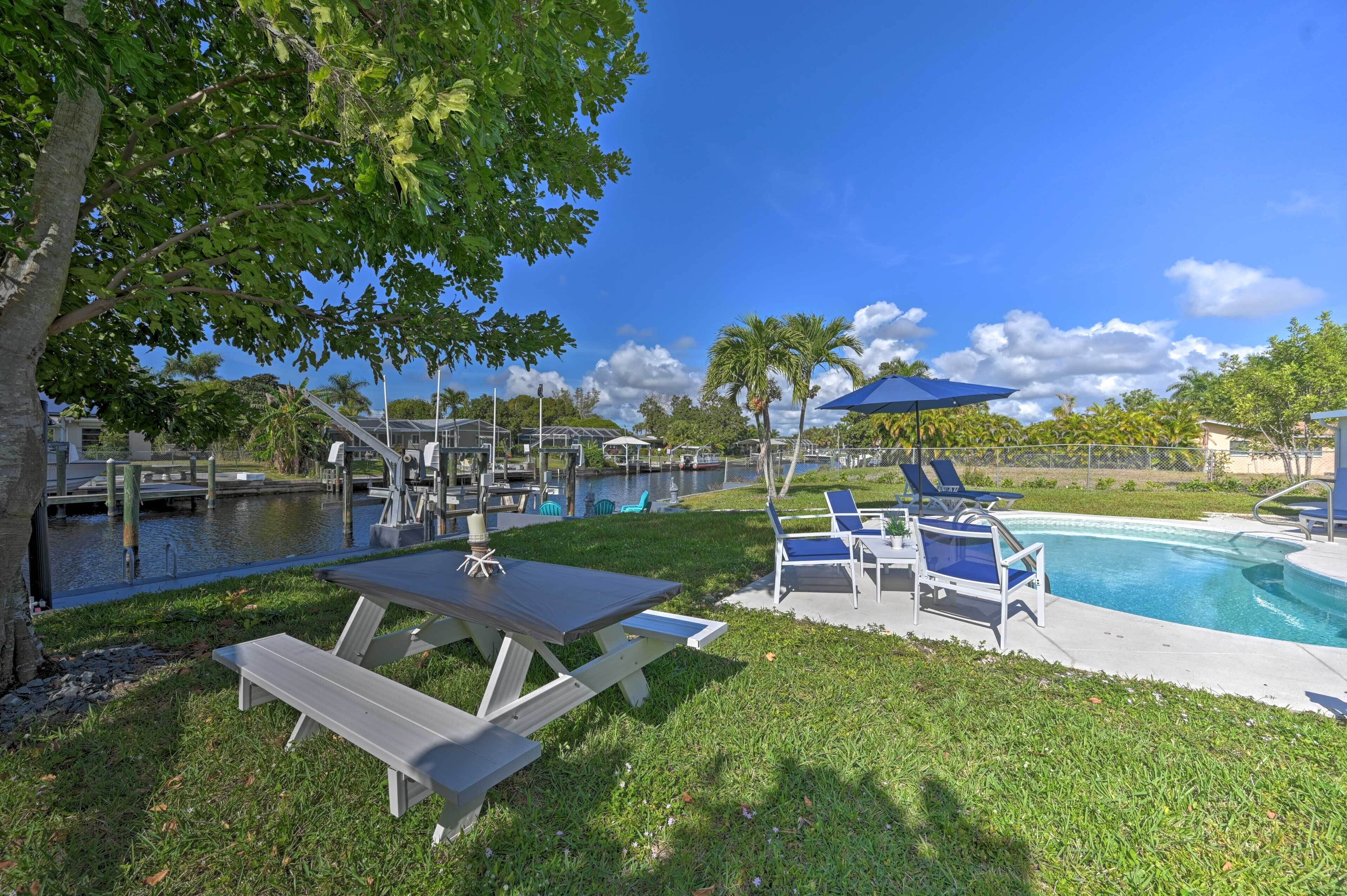 A poolside area with a picnic table, lounge chairs, and a clear view of the water.
