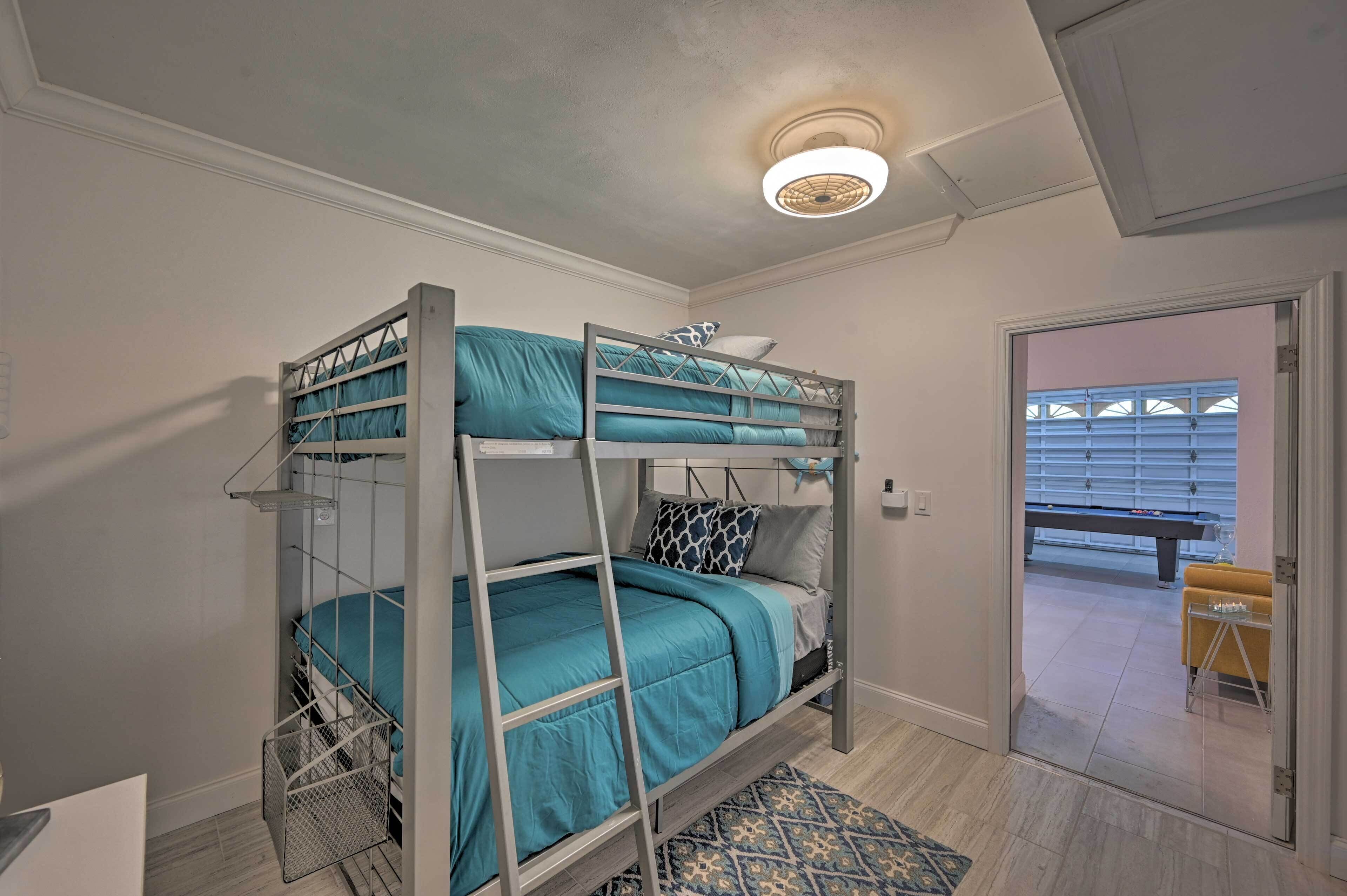Une chambre avec un lit superposé, une échelle, un tapis à motifs et une porte donnant sur un balcon équipé d’un banc.