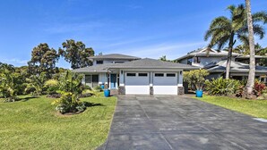 A two-story house with a garage, surrounded by a well-maintained lawn and tropical plants. - Spacious Kauai Getaway < 1 Mi to the Ocean! (Princeville)