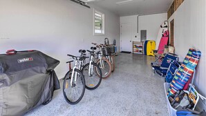 A garage with bicycles, a covered grill, and a storage bin with colorful items. - Spacious Kauai Getaway < 1 Mi to the Ocean! (Princeville)
