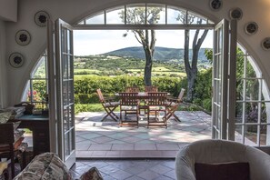 An open patio with a table and chairs, a view of a green landscape, and a large arched window. - S315 - Sirolo, single villa with panoramic garden (Montefreddo)