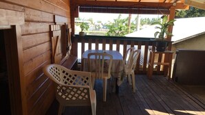A wooden deck with a table and chairs, a potted plant, and a view of the outside. - Charming, air-conditioned chalet in the heart of Saint-Leu, 5 minutes from the beach (Saint-Leu)