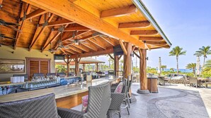 An outdoor bar area with wicker chairs, a wooden ceiling, and a view of the ocean.