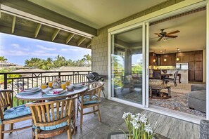A covered patio with a dining table set for four, a grill, and a view of the kitchen and living area through glass doors. - Sun-soaked Waikoloa Retreat w/ Private Lanai! (Waikoloa)