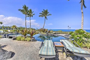A poolside area with lounge chairs, palm trees, and a view of the ocean. - Sun-soaked Waikoloa Retreat w/ Private Lanai! (Waikoloa)