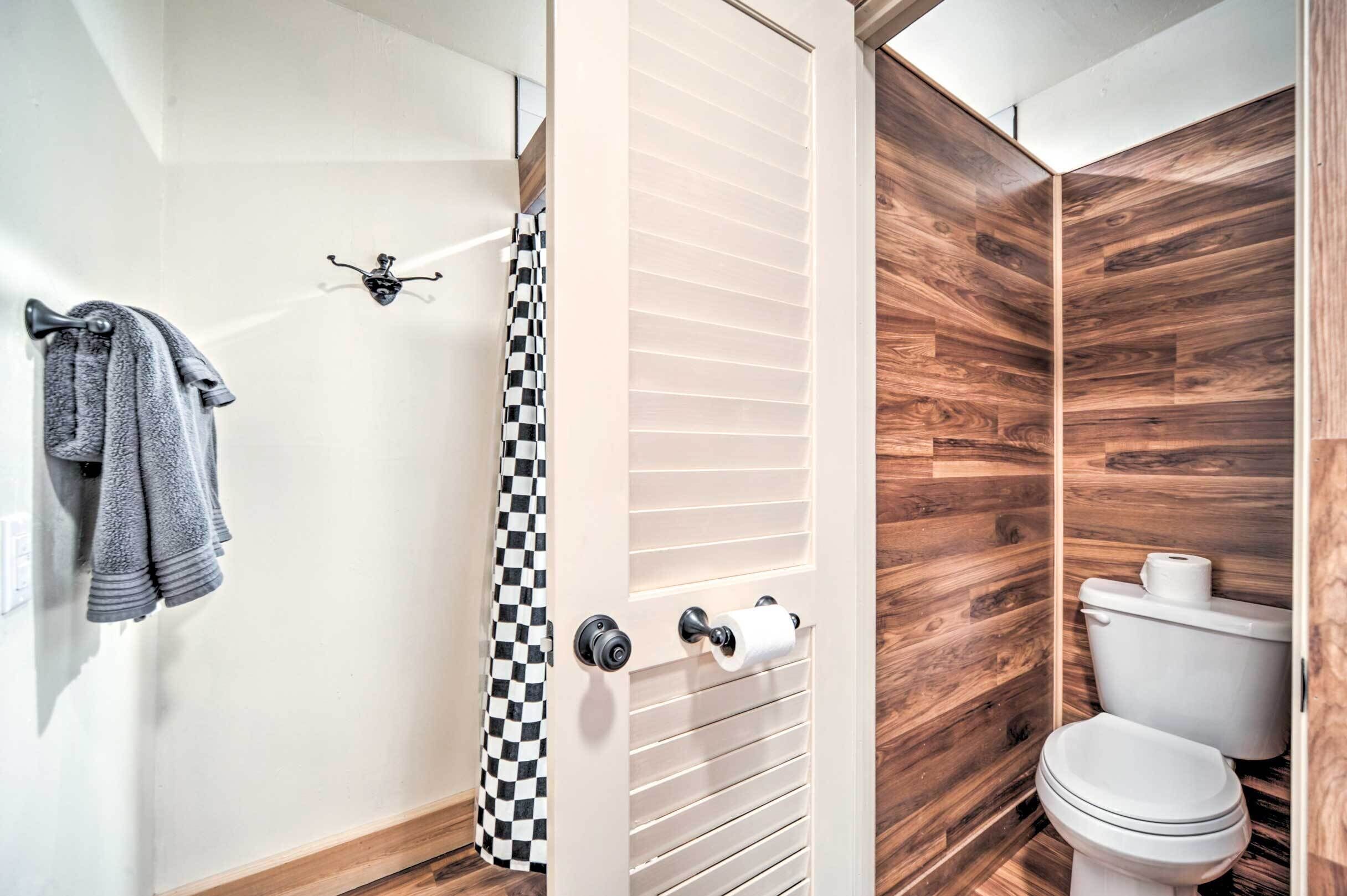 A modern bathroom with a wooden wall, a toilet, and a towel rack with towels.