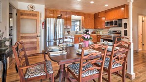 A spacious kitchen with wooden cabinets, a stainless steel refrigerator, a microwave, and a dining area with a large wooden table and chairs. - 1 Mi to Dtwn Fredericksburg: Quiet Getaway w/ Yard (Fredericksburg)