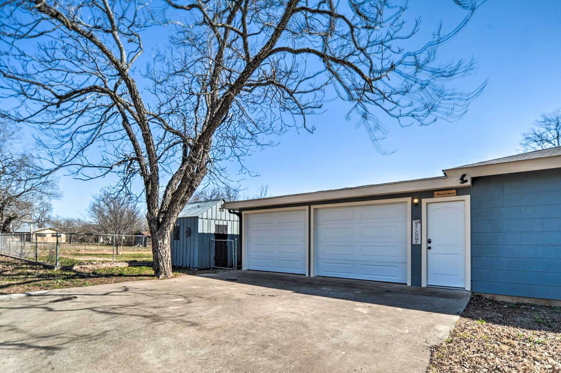 Un bâtiment à deux étages avec un garage, un arbre devant et un ciel bleu dégagé.