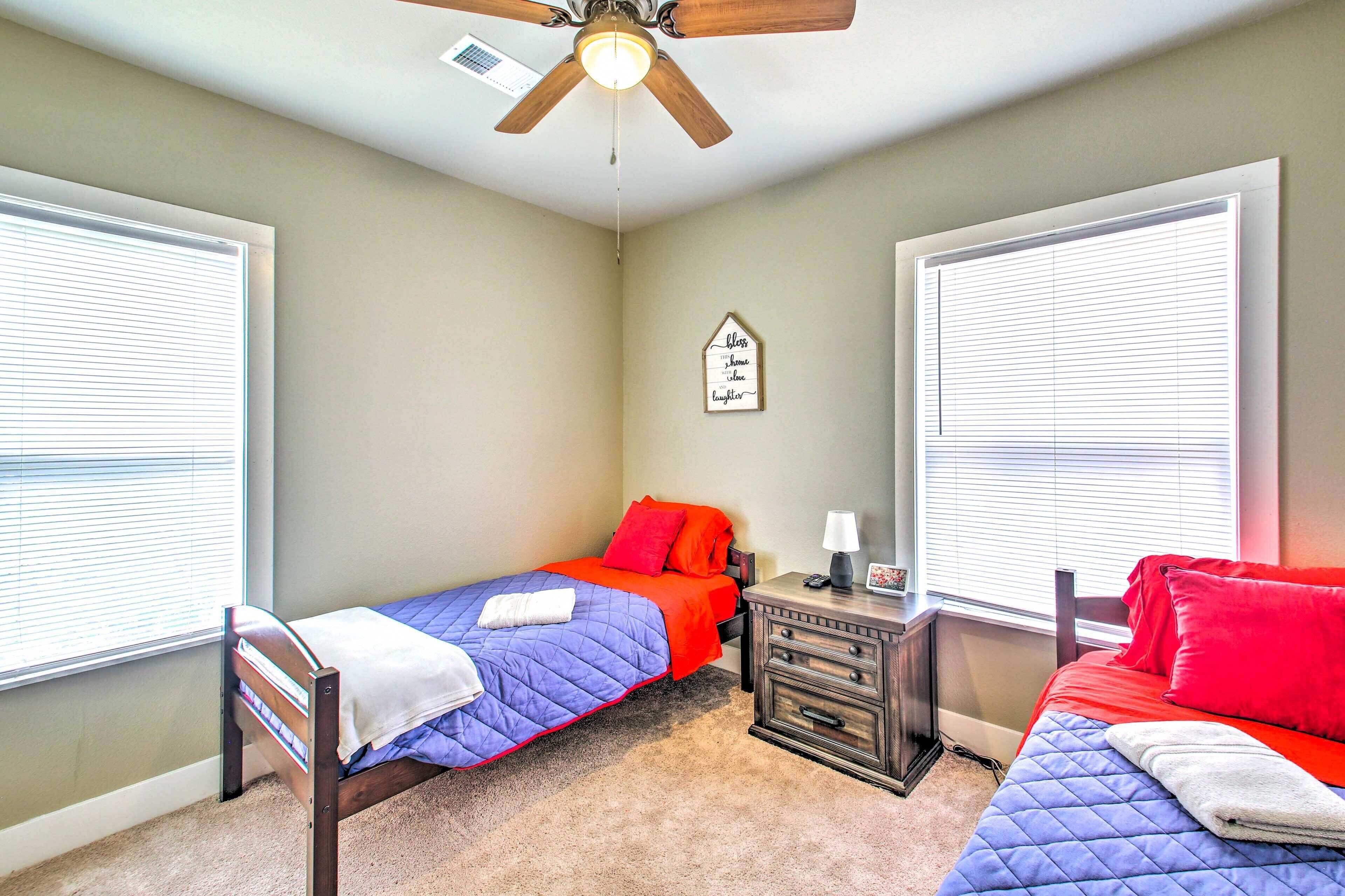 A bedroom with two beds, a ceiling fan, and a nightstand.