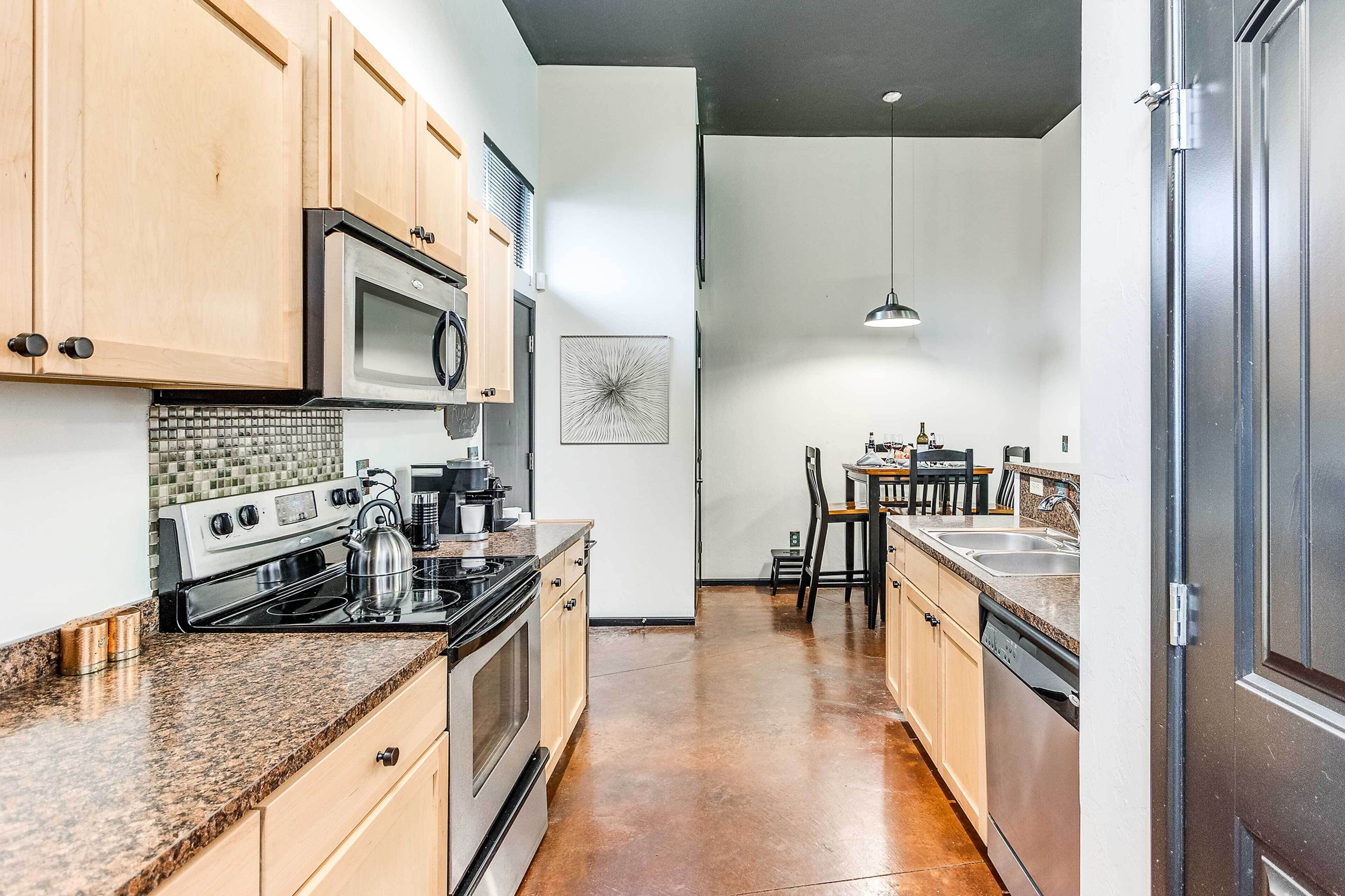 A kitchen with wooden cabinets, stainless steel appliances, a granite countertop, and a tiled backsplash.
