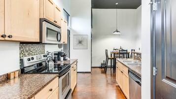 A kitchen with wooden cabinets, stainless steel appliances, a granite countertop, and a tiled backsplash.