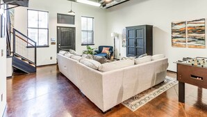 A modern living room with a sectional sofa, a dark wooden cabinet, and a foosball table. - Norman, Oklahoma, Vacation Rental 1 Mi to OU! (Norman)