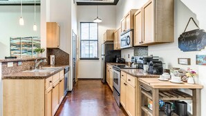 A modern kitchen with wooden cabinets, a built-in oven, a microwave, and a coffee station. - Norman, Oklahoma, Vacation Rental 1 Mi to OU! (Norman)