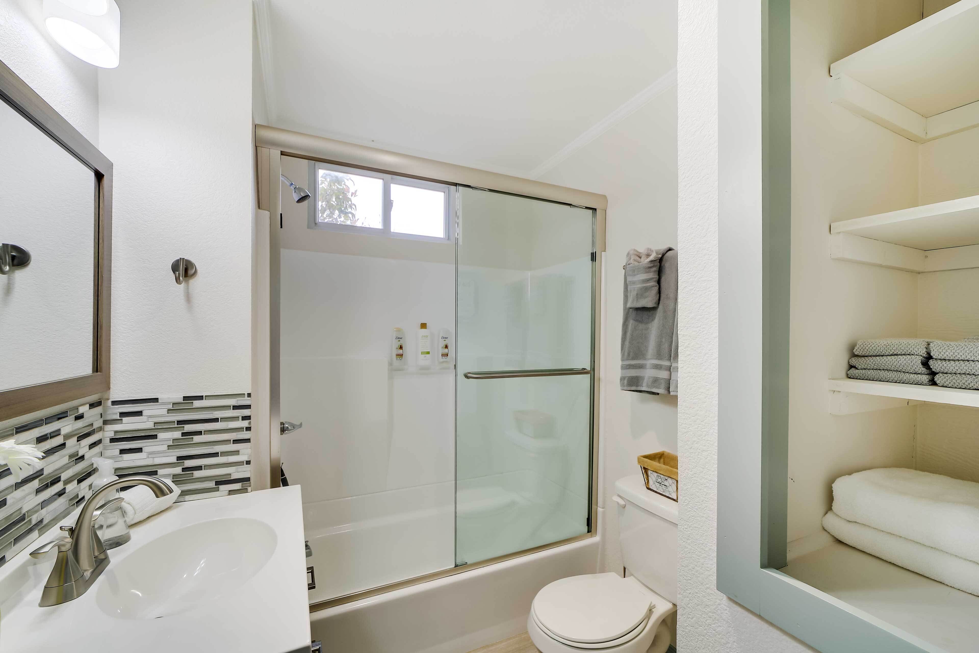 Een moderne badkamer met een douchecabine van glas, een wit wastafelmeubel en een toilet.