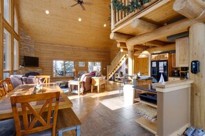 Cozy retreat with a dining table, sofa, and kitchenette, plus a staircase to a balcony with lush views.