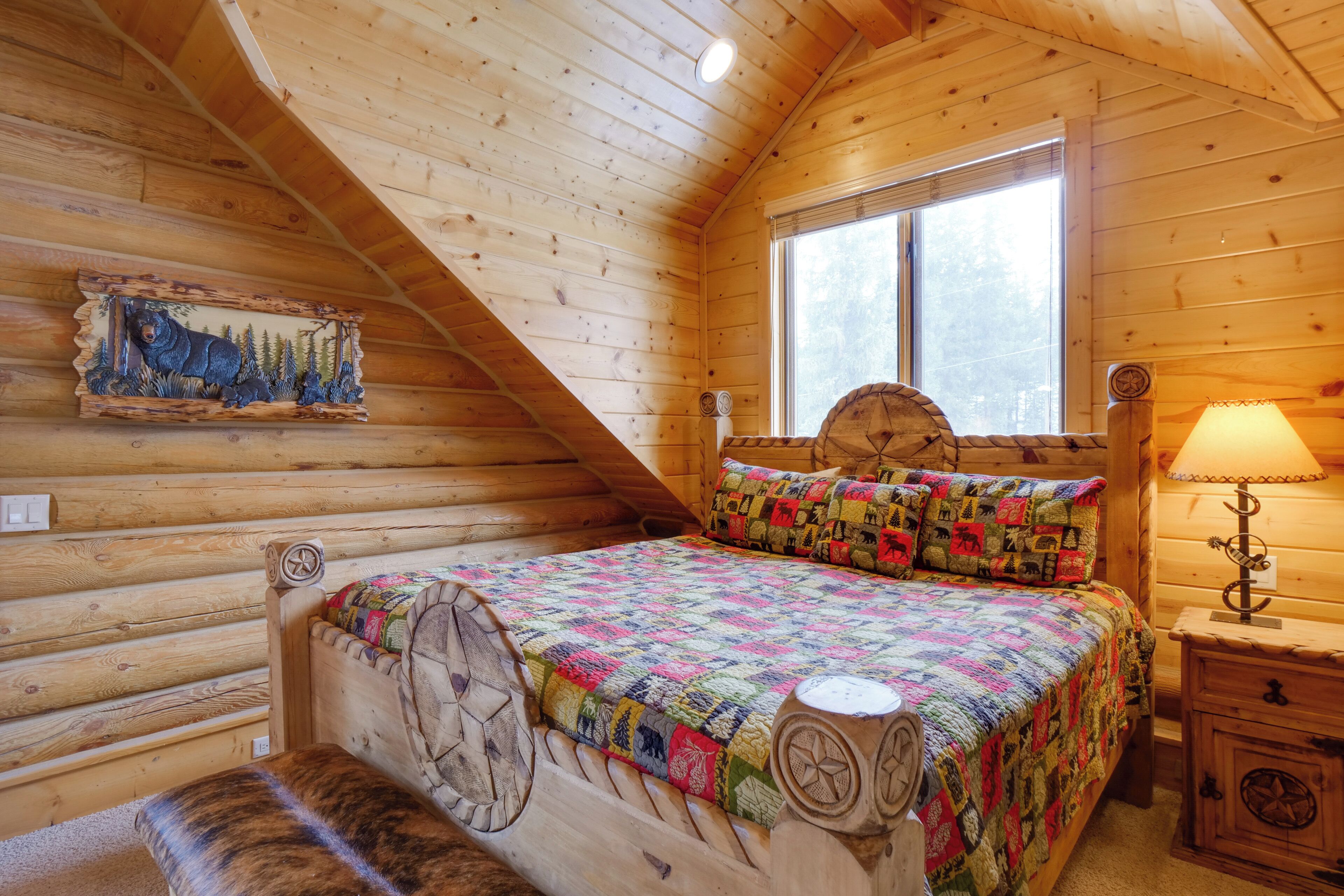 A log cabin bedroom with a wooden bed, a window, and a wall-mounted clock.