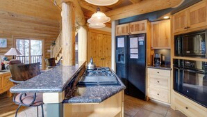 Eine Küchenlandschaft in einer Blockhütte mit einer zentralen Kochinsel, Holzschränken und modernen Geräten.