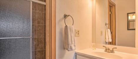 Un baño con ducha, lavamanos y espejo.