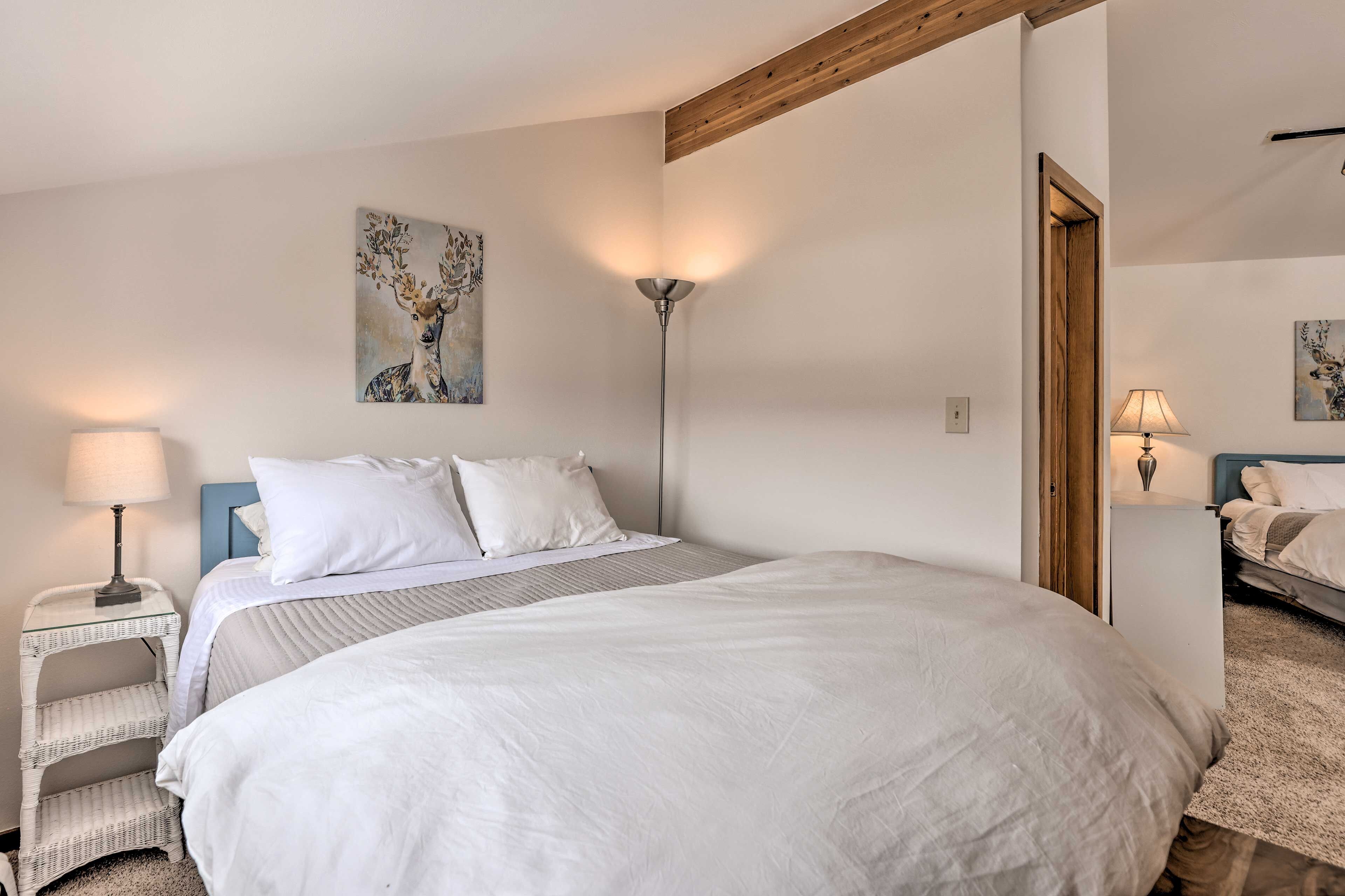 Un dormitorio con una cama grande, una mesita de noche con lámpara y una obra de arte colgada en la pared.