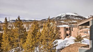 Un edificio moderno con techo plano, rodeado de terreno cubierto de nieve y árboles de coníferas.