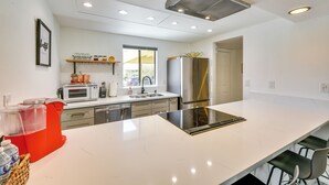 Una cocina moderna con encimera blanca, electrodomésticos de acero inoxidable y horno integrado.