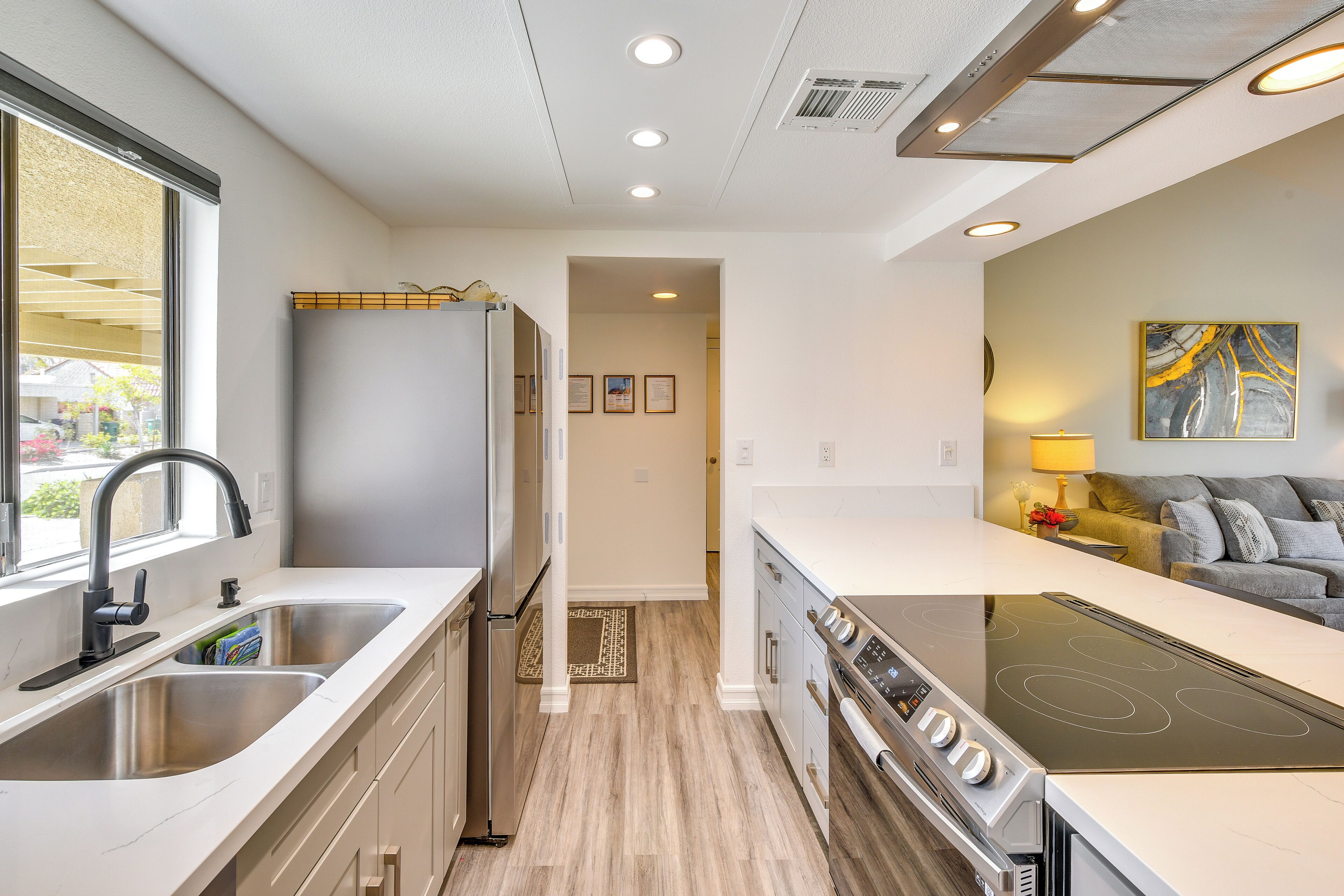 A modern kitchen with stainless steel appliances, a large island, and a view to a living area.