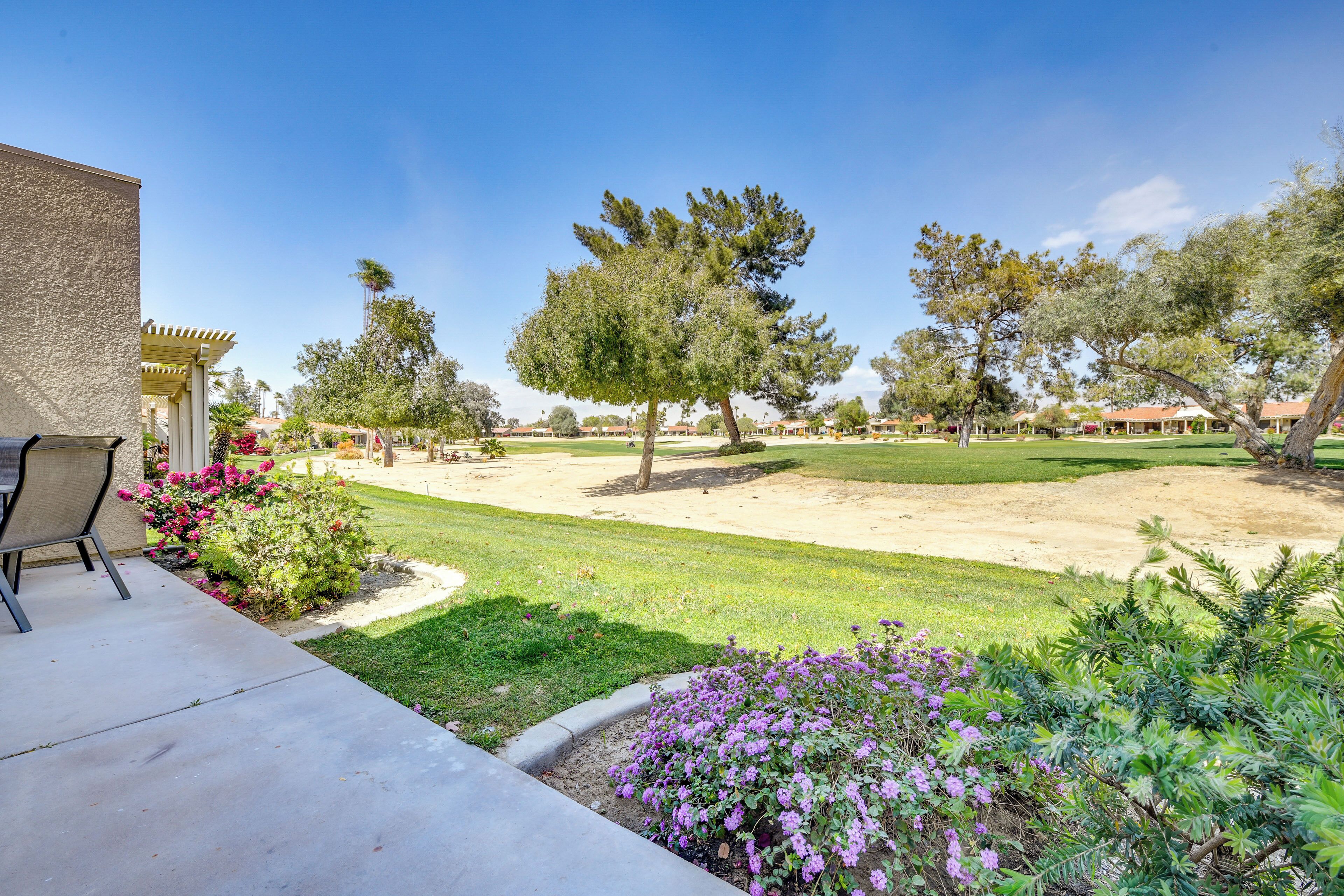 A residential property with a patio, a lawn, and a variety of trees and shrubs.