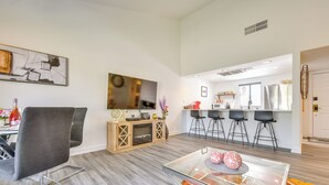 Una sala moderna con un sillón tapizado gris, una mesa de centro de vidrio y una alfombra colorida.
