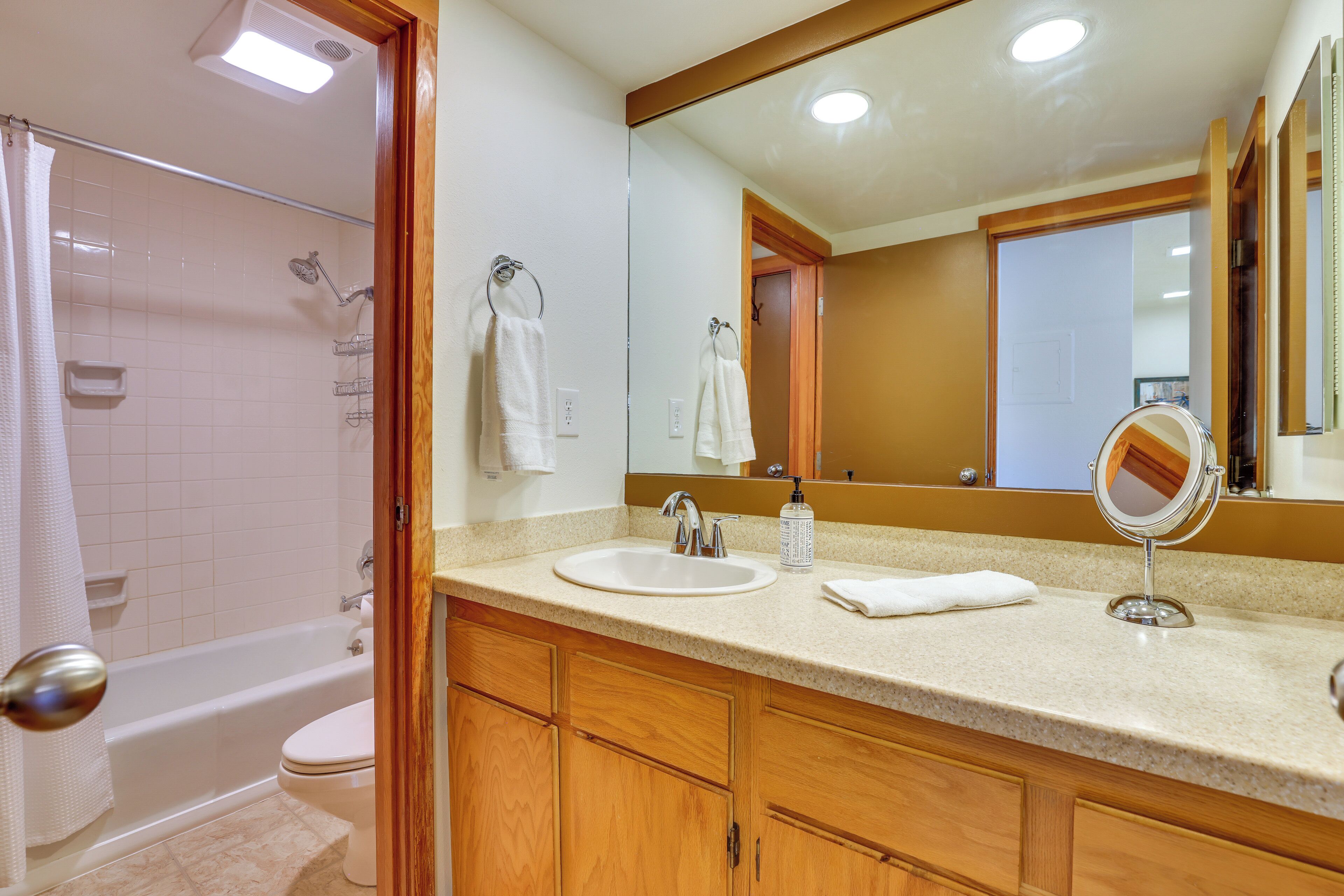 A bathroom with a bathtub, toilet, sink, and a large mirror.