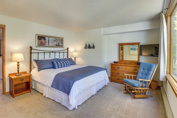 A bedroom with a bed, nightstands, a dresser, a chair, and a mirror.