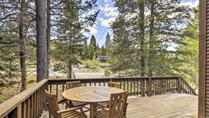 A wooden deck with a round table and chairs, surrounded by tall trees and a clear sky. - Game Room: Mountain Chalet 5 Mi to Donner Lake (Truckee)