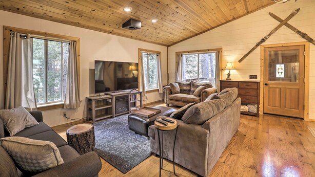 A cozy living room with a fireplace, wooden ceiling, and large windows. - Game Room: Mountain Chalet 5 Mi to Donner Lake (Truckee)