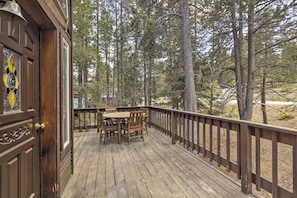 Une terrasse en bois avec une table et des chaises, entourée d’arbres.