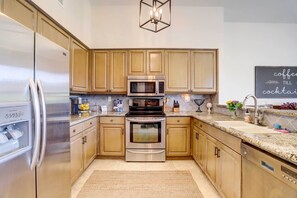 A modern kitchen with stainless steel appliances, wooden cabinets, and a granite countertop. - Full Palm Valley CC Access: Luxe Gem w/ Epic Views (Palm Desert)