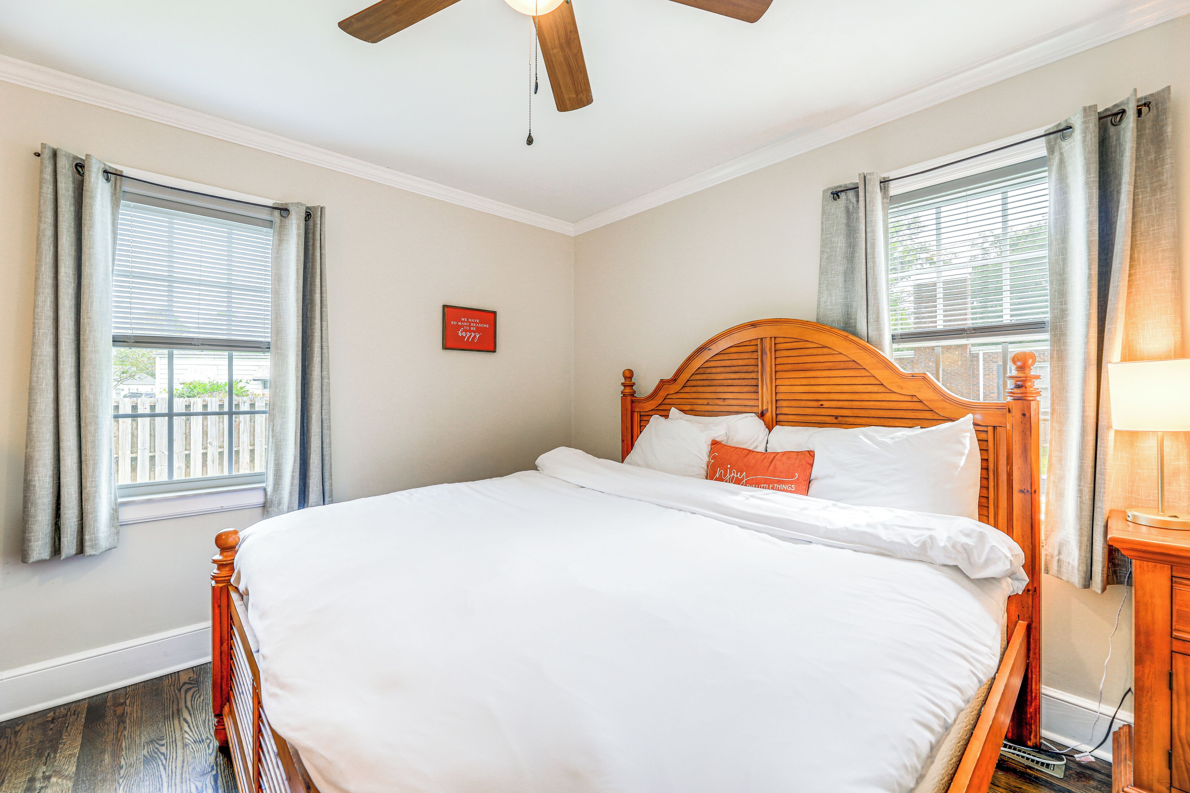 A bedroom with a wooden bed, a ceiling fan, and a window with curtains.