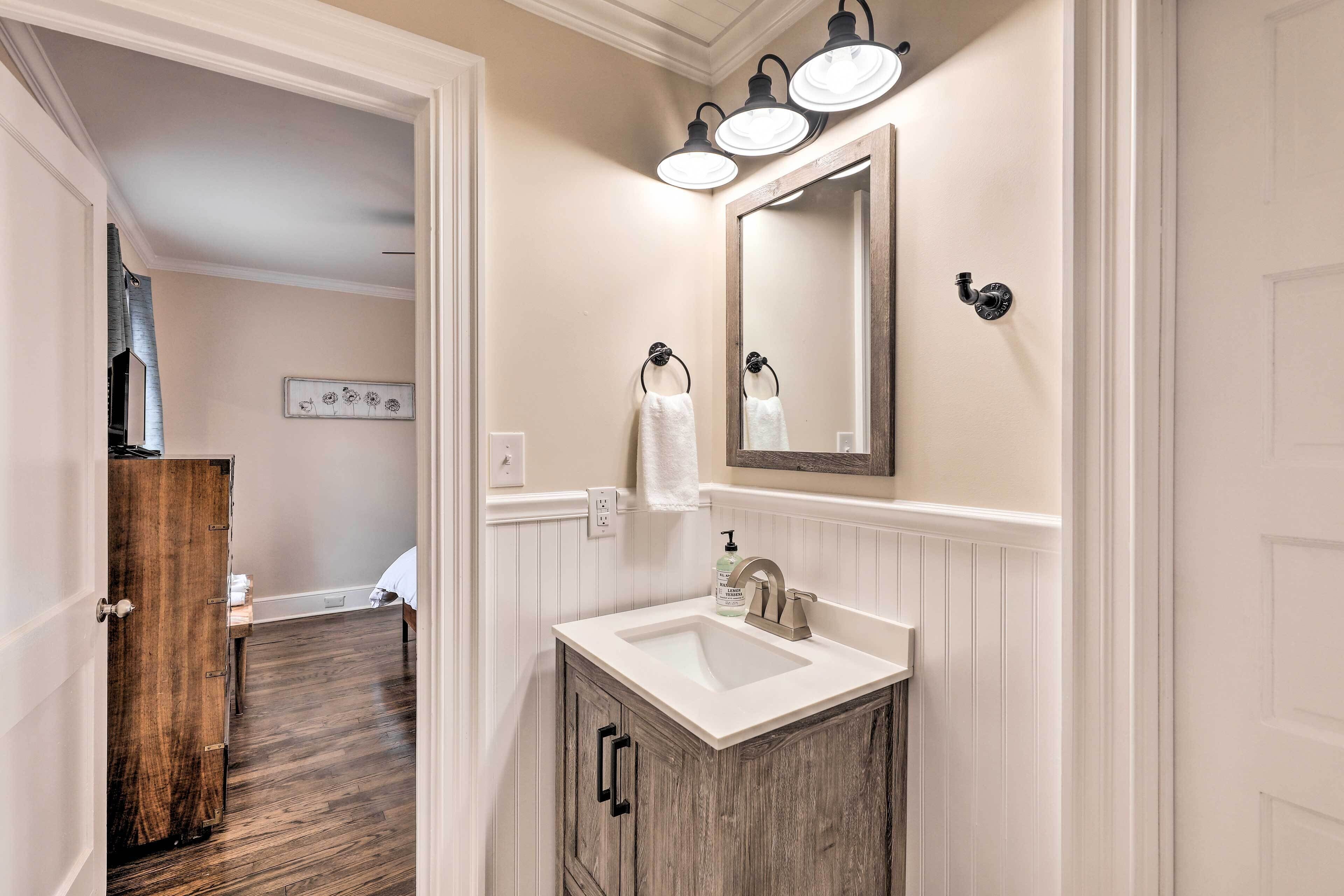 A bathroom with a wooden vanity, a sink, and a mirror with three lights.