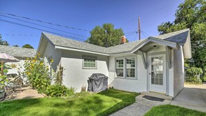 A single-story house with a white exterior, a garage door, and a small front yard with grass and a covered grill. - Well-equipped Cody Cottage: 2 Mi to Cody Rodeo! (Cody)