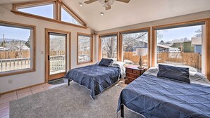 A bedroom with two beds, large windows, a ceiling fan, and a view of the backyard. - Charming Buena Vista Home w/ Hot Tub + Deck! (Buena Vista)